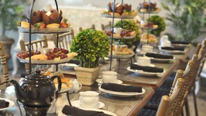 Une table à manger dressée avec plusieurs services à thé, des assiettes et une variété de plats.