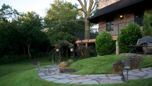 Une maison en pierre à deux étages, avec un chemin de pierre menant à une terrasse en bois.