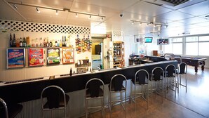 A bar area with a counter, bar stools, and a pool table.