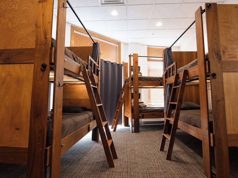 A room with bunk beds, wooden walls, and a carpeted floor.