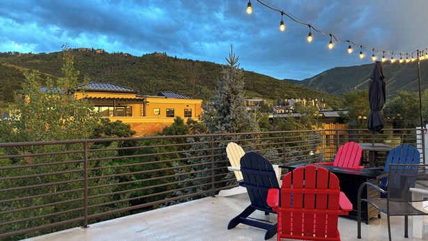 Une terrasse avec des sièges extérieurs, une vue sur une montagne et des guirlandes lumineuses.