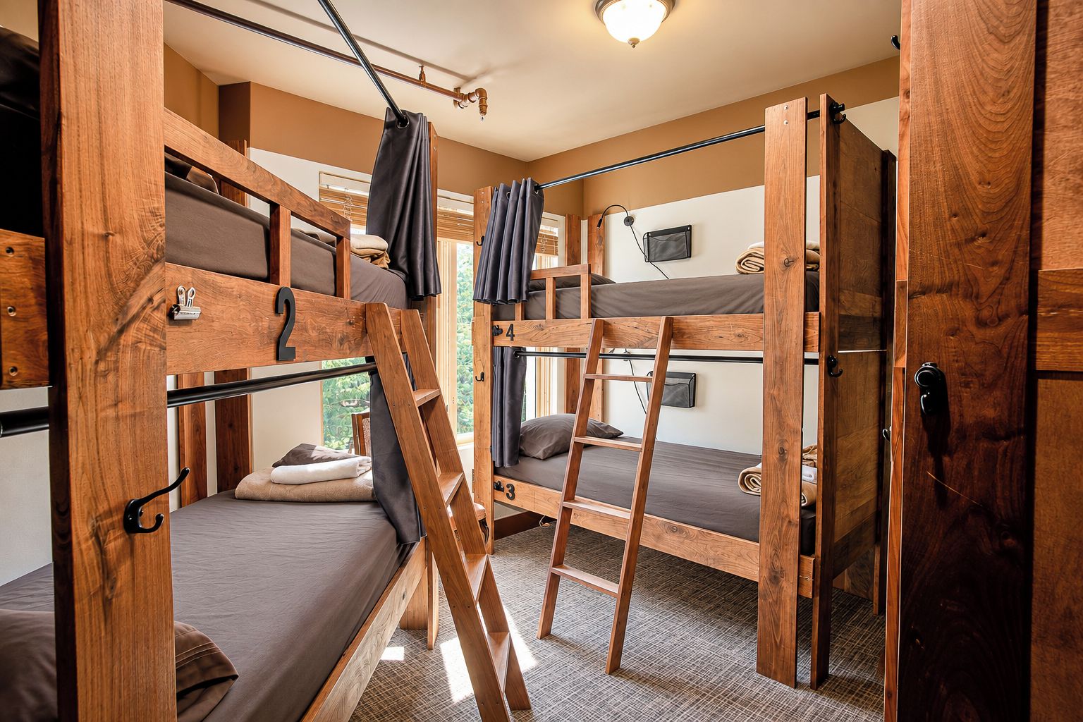 A dormitory room with bunk beds, a ladder, and a door.