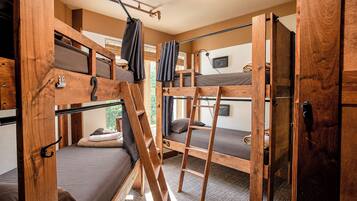 A dormitory room with bunk beds, a ladder, and a door.
