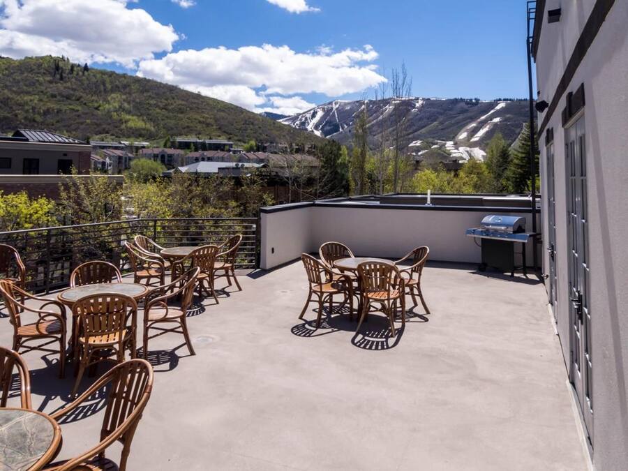 Terraza en la azotea con mobiliario exterior y una parrilla, con vistas a un paisaje montañoso.