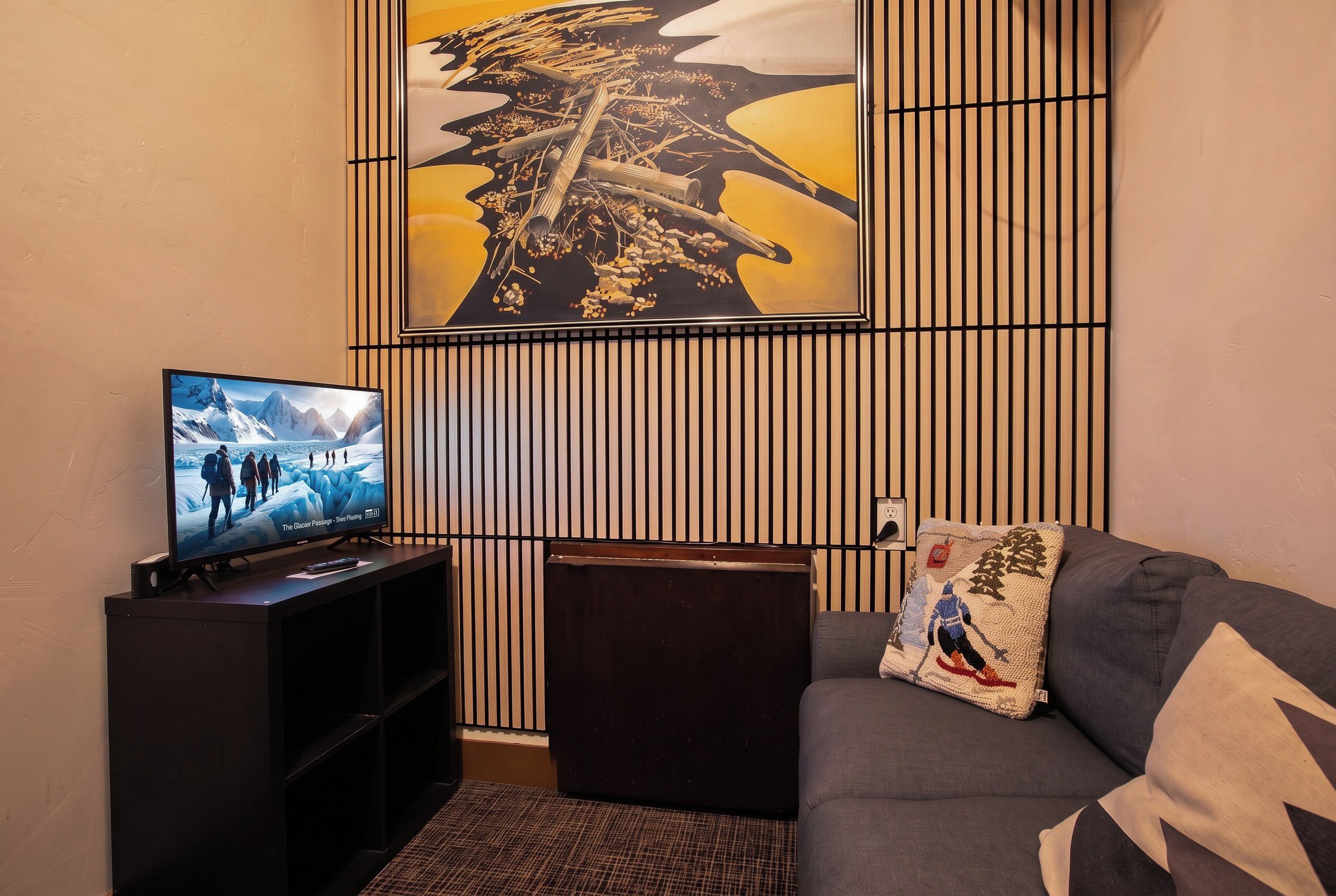 Un salon comprenant un téléviseur, un canapé, un panneau décoratif mural et une petite table.