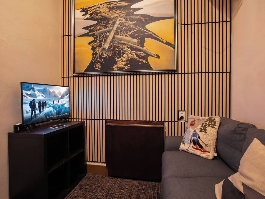 Un salon comprenant un téléviseur, un canapé, un panneau décoratif mural et une petite table.