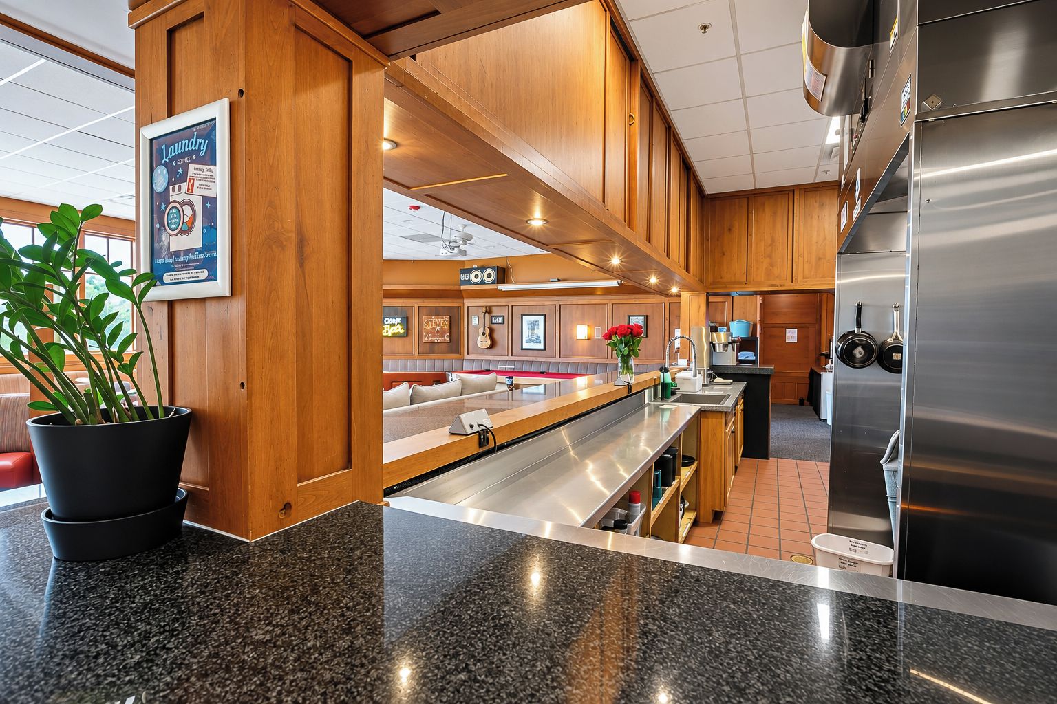 A modern kitchen with stainless steel appliances, wooden cabinetry, and a granite countertop.