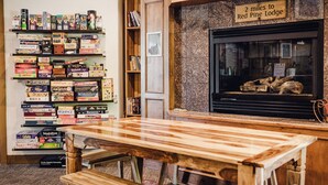 Une pièce chaleureuse avec une cheminée, une table en bois et des étagères remplies de jeux de société.