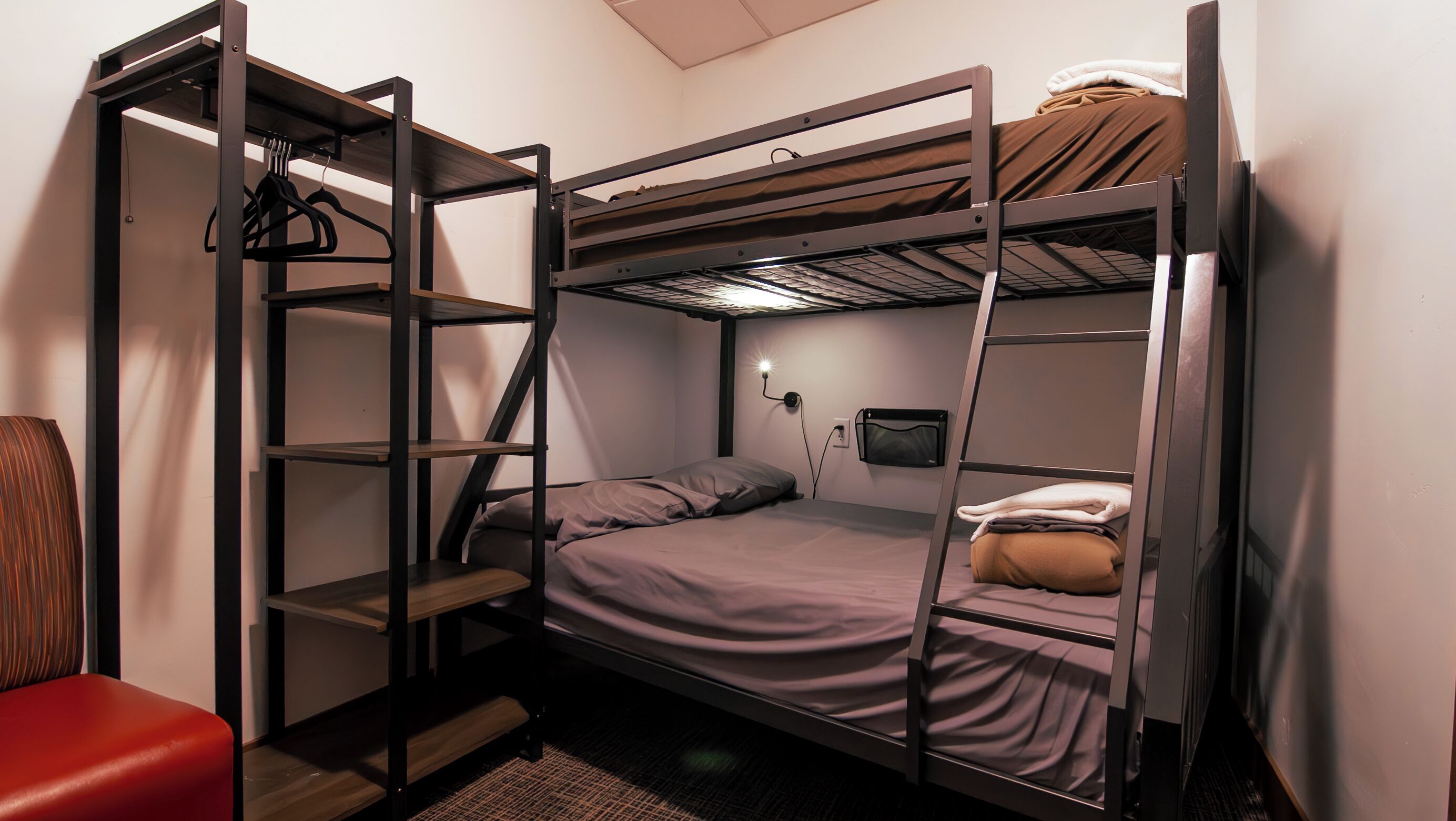 A bunk bed room with a desk and a chair.