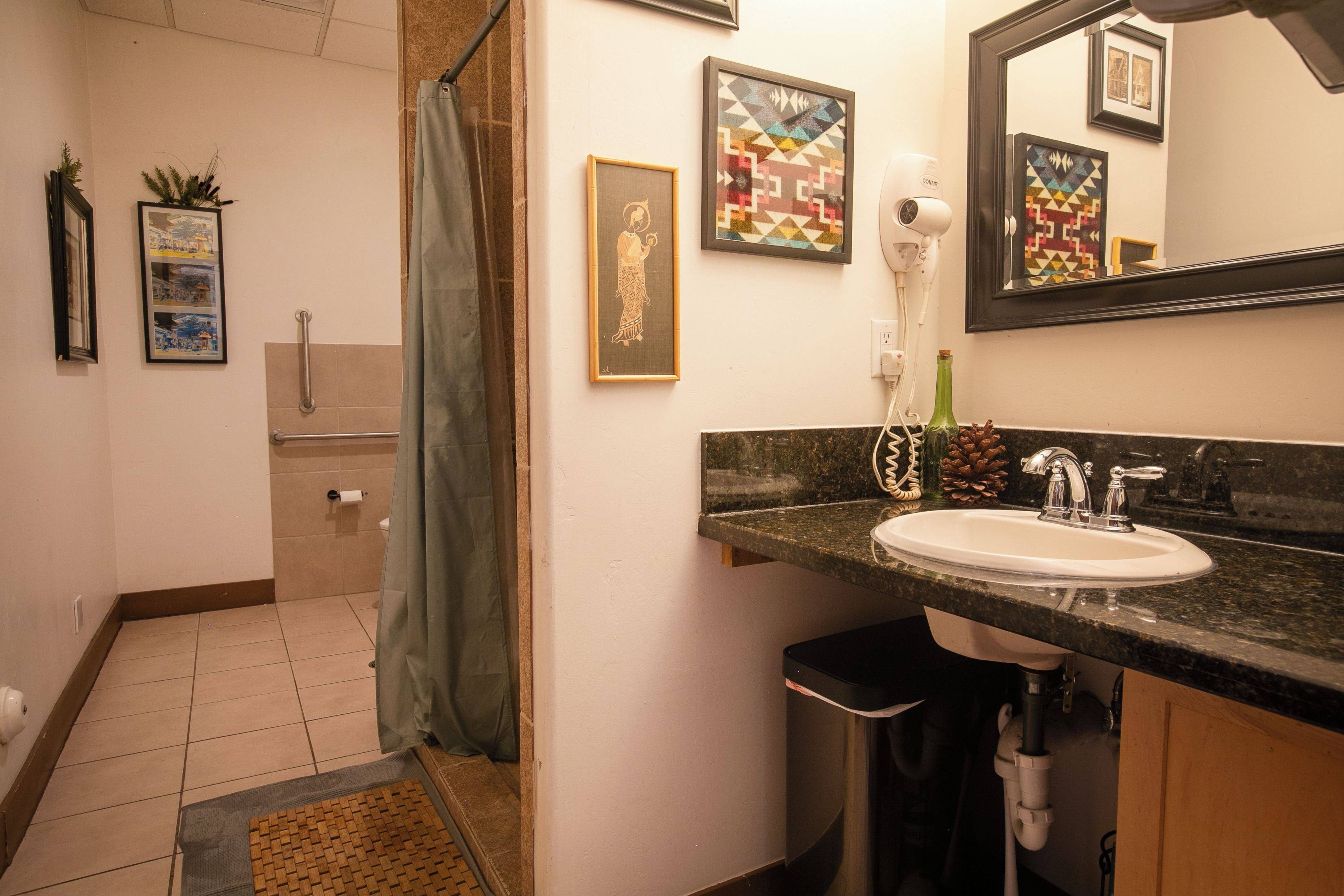 A bathroom with a sink, mirror, and framed artwork on the wall.