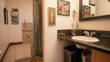 A bathroom with a sink, mirror, and framed artwork on the wall.