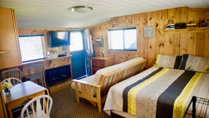 Una camera in stile baita con arredamento in legno, un letto con biancheria a righe, una scrivania con sedia e una finestra con persiane.
