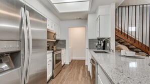 A modern kitchen with stainless steel appliances, a granite countertop, and a wooden staircase. - South Austin Creekside Retreat!  (Austin)