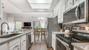 A modern kitchen with a skylight, stainless steel appliances, and a dining area with natural light. - South Austin Creekside Retreat!  (Austin)