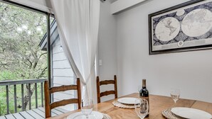 A dining table set with plates, glasses, and a wine bottle, with a view of trees through a window. - South Austin Creekside Retreat!  (Austin)