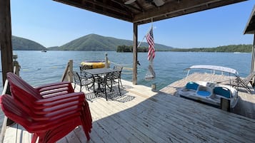 Une terrasse en bois avec une table et des chaises, un drapeau américain et un bateau.