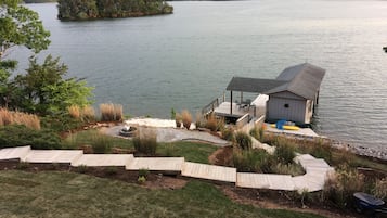 Une cabane au bord du lac, dotée d’une terrasse, d’un petit abri et d’un quai s’avançant dans l’eau.