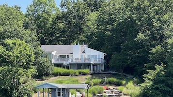 Une maison au bord du lac, dotée d’un quai, d’un abri à bateaux et d’une petite terrasse ornée d’une statue.