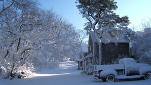 A snow-covered wooden cabin with a truck parked in front. - Provincetown: Water view, 3 BR House, Parking, Free Wifi, outdoor shower, beach! (Provincetown)