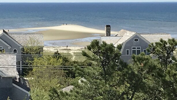 A coastal property with a sandy beach, a stone chimney, and a view of the ocean. - Provincetown: Water view, 3 BR House, Parking, Free Wifi, outdoor shower, beach! (Provincetown)