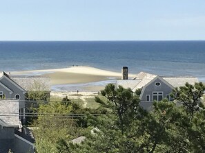 A coastal property with a sandy beach, a stone chimney, and a view of the ocean. - Provincetown: Water view, 3 BR House, Parking, Free Wifi, outdoor shower, beach! (Provincetown)