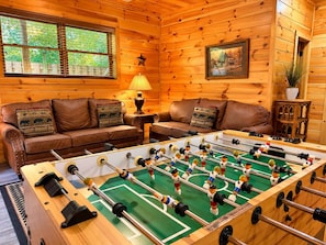 A cozy room with a foosball table, leather sofas, and a star decoration on the wall.