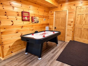 A room with a pool table, wooden walls, and a door.