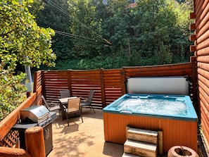 Un jardin avec un jacuzzi, un barbecue et un espace salon extérieur.