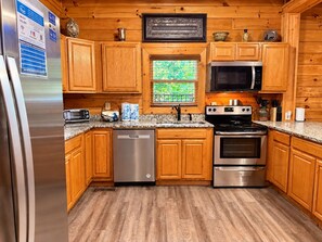 A kitchen with wooden cabinets, stainless steel appliances, a microwave, a stove, and a dishwasher.