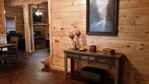 Un interno in legno con un tavolo da pranzo, sedie, un camino e un quadro appeso al muro.