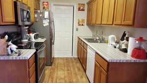 A kitchen with wooden cabinets, a stainless steel refrigerator, a microwave, a toaster, and a sink. - 3 bedroom, 2 bath house. Sleeps 6. Close to 76 Hwy strip (Branson)