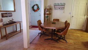 A dining room with a wooden table, leather chairs, a wooden side table, a mirror, a wreath, and a shelf with decorative items. - 3 bedroom, 2 bath house. Sleeps 6. Close to 76 Hwy strip (Branson)