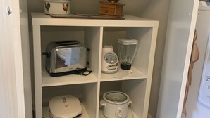 A compact kitchen with a toaster, blender, slow cooker, and a vintage coffee grinder on the shelves. - Cozy Country Apartment in Heart of Geauga County (Newbury)