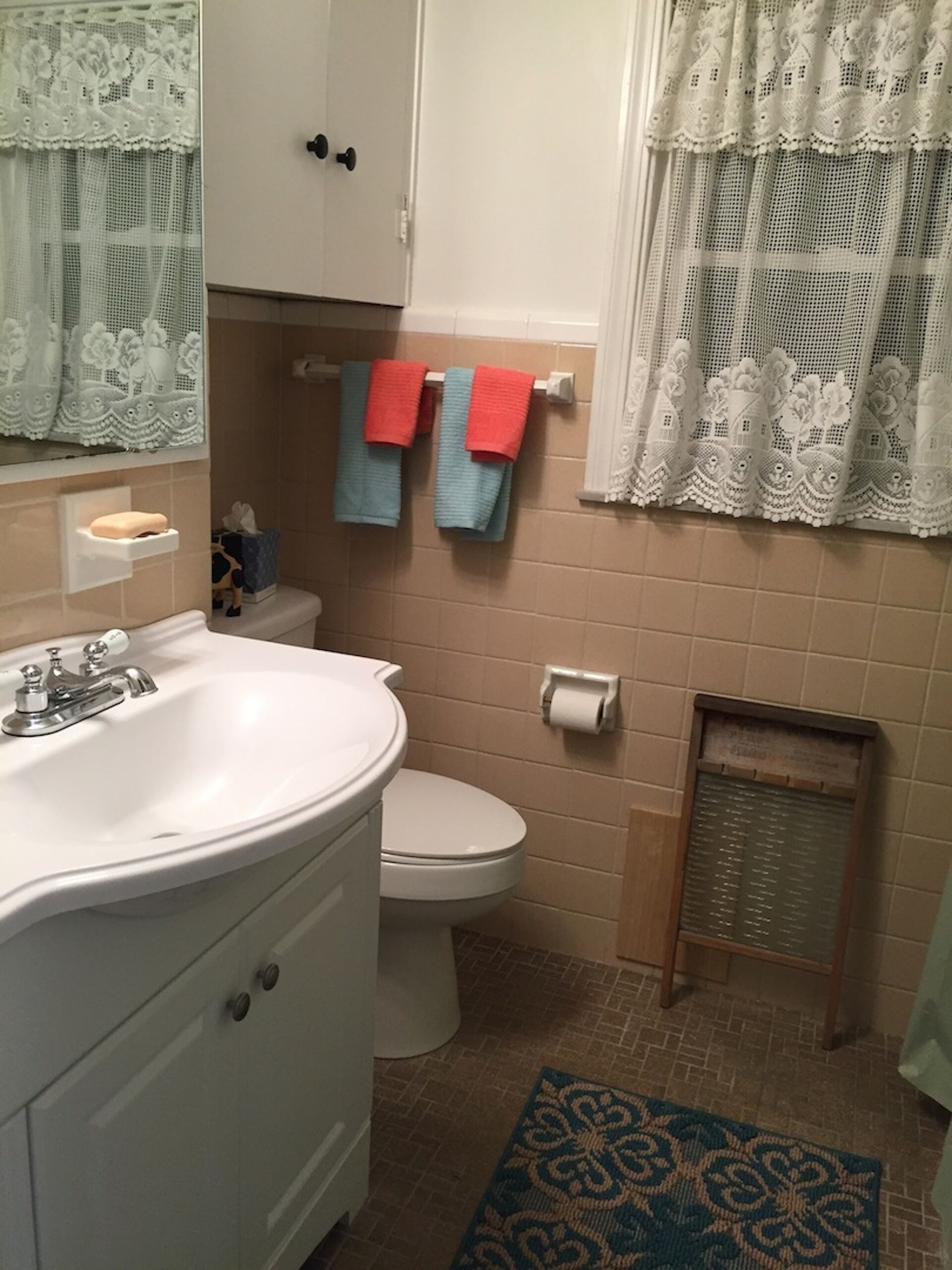 Une salle de bain avec un lavabo blanc, des toilettes et un porte-serviettes avec des serviettes rouges et bleues.