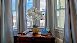 A vintage suitcase with a vase of white orchids on a windowsill, a book, and a pair of glasses. - Captain Sawyer's Bed & Breakfast (Boothbay Harbor)