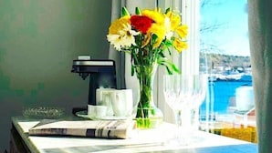 A marble countertop with a coffee maker, a vase with flowers, and two glasses. - Captain Sawyer's Bed & Breakfast (Boothbay Harbor)