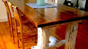 A dining table with a rustic design, surrounded by wooden chairs. - Captain Sawyer's Bed & Breakfast (Boothbay Harbor)