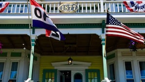 A building with a porch, a flag with the number 1877, and an American flag. - Captain Sawyer's Bed & Breakfast (Boothbay Harbor)