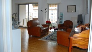 A spacious living room with a brown leather sofa, a wooden coffee table, and a piano. - Apartment/ flat - Colmar (Colmar)