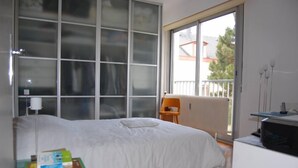 A bedroom with a large window, a bed, a chair, and a desk with a computer. - Apartment/ flat - Colmar (Colmar)