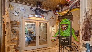 Cine con una estrella en la pared, un sillón de director y una estatua de monstruo verde.