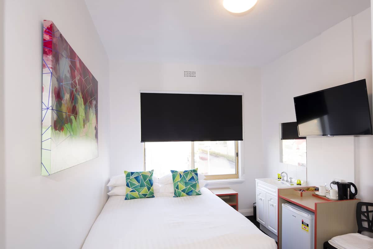 Une chambre d’hôtel avec un lit, une petite kitchenette, une télévision et une fenêtre donnant sur un paysage agréable.