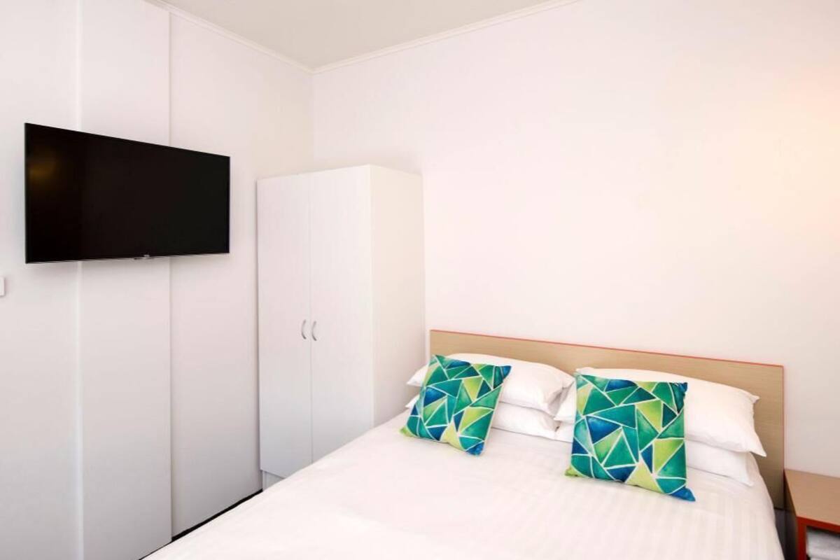 Une chambre d’hôtel avec un lit, un téléviseur fixé au mur et une armoire.