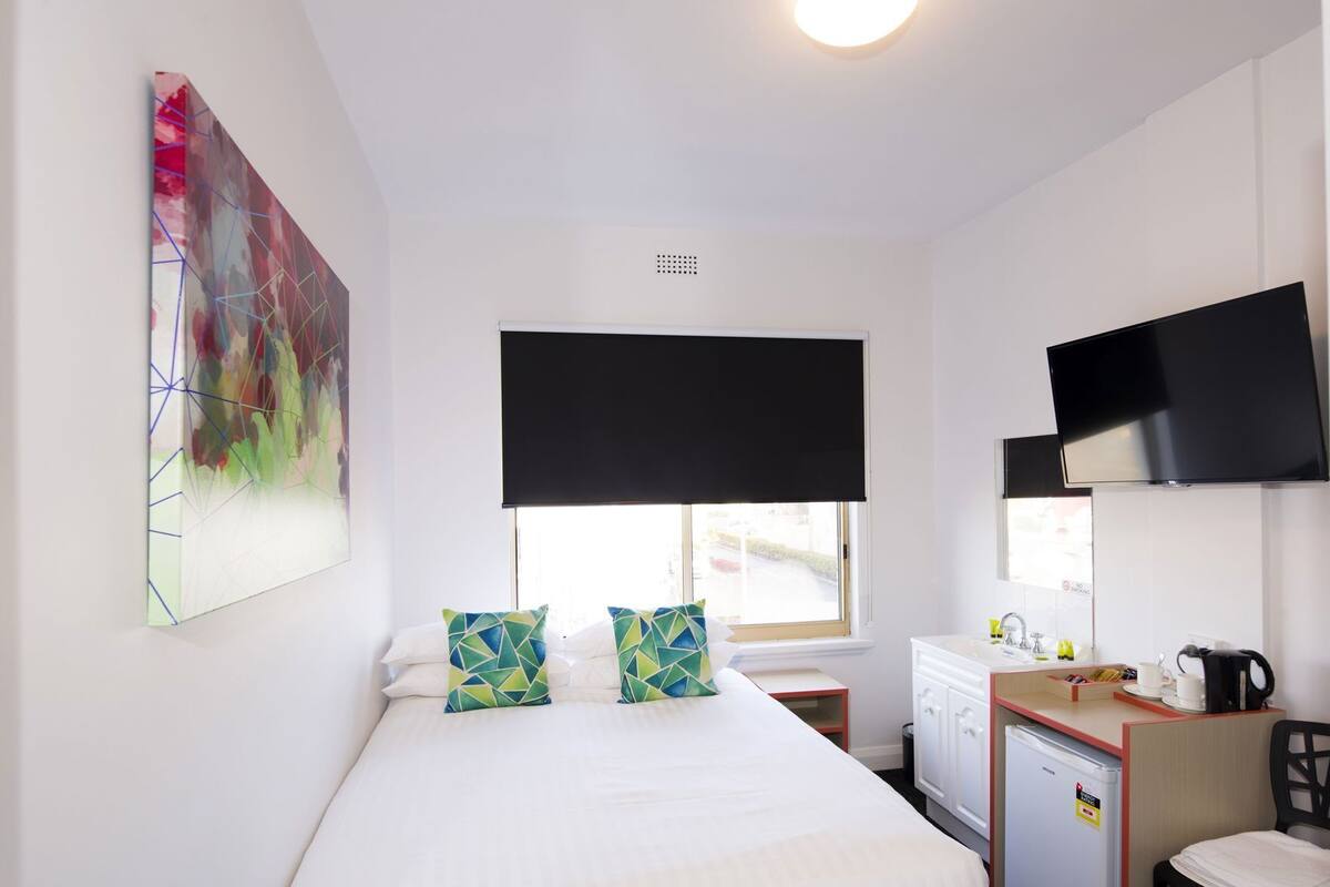 Une chambre d’hôtel avec un lit, un bureau, une télévision et une fenêtre.