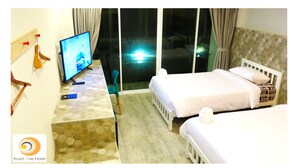 Una habitación de hotel con televisión, un escritorio con control remoto y dos camas.