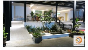 Un vestíbulo de hotel con una escalera, plantas en macetas y una zona de estar.