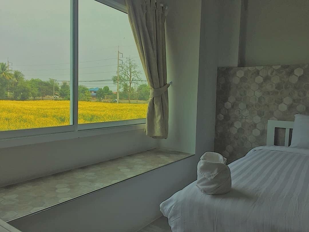 Un dormitorio con un ventanal grande, una cama con almohada blanca y un papel tapiz estampado.