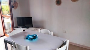Un espace repas comprenant une table, des chaises, un téléviseur et des éléments décoratifs fixés au mur.