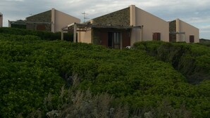Eine moderne Villa mit Natursteinfassade, flachem Dach und überdachter Terrasse.
