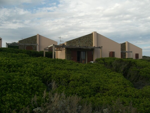 Una villa moderna con fachada de piedra, techo plano y zona de patio cubierta.